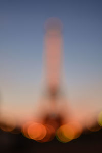 Defocused image of illuminated factory against sky at sunset