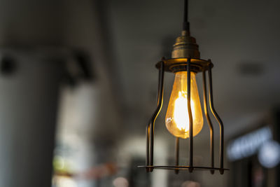 Low angle view of illuminated light bulb hanging from ceiling