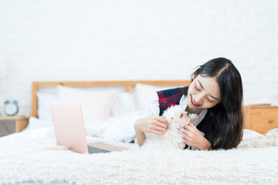 Woman using mobile phone on bed