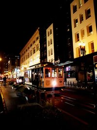 Cars on illuminated city against sky at night