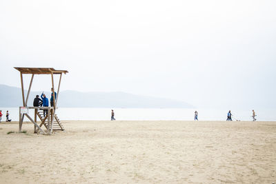 People on beach against clear sky