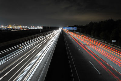 Light trails on road against sky at night