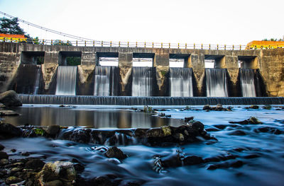 Water flowing in dam against sky
