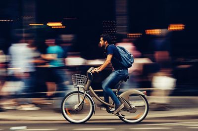 Full length side view of man riding bicycle on street