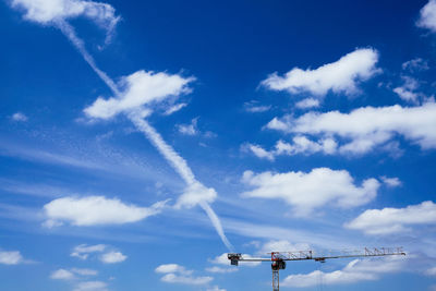 Low angle view of crane against cloudy blue sky