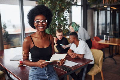 Black woman with smartphone standing in front of group of multi ethnic people 