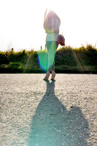 Rear view of man standing on grassy landscape against sky