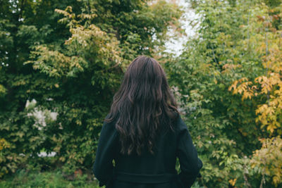 Rear view of woman standing against trees