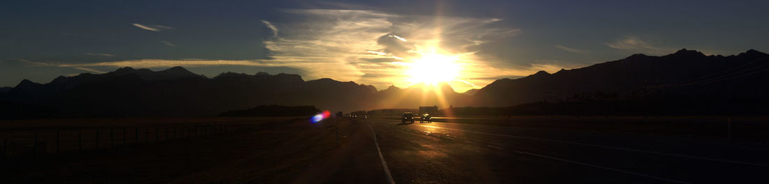 Cars on road against sky during sunset