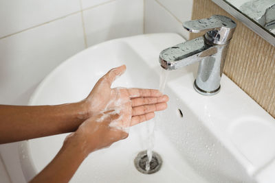 Cropped image of person washing hands