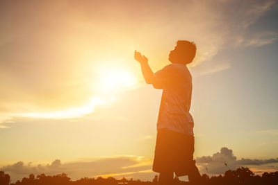 Rear view of silhouette man standing against sky during sunset