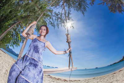 Portrait of woman sitting on swing at beach