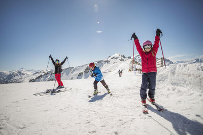 Full length of family enjoying while skiing against clear sky