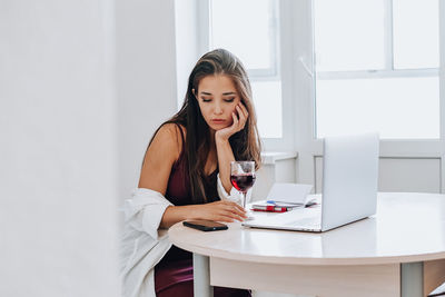 Young woman using phone while sitting on table