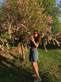 Full length of young woman standing by flower tree