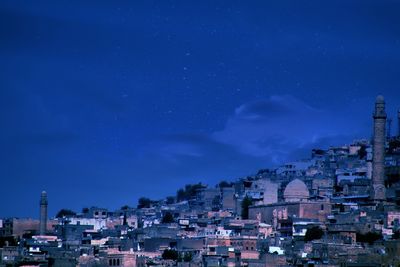 High angle view of illuminated buildings against blue sky