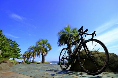 Bicycle by rock on pier against sky