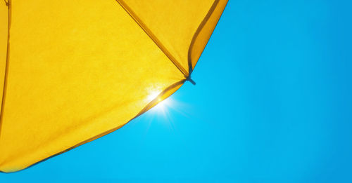 Low angle view of yellow umbrella against sky