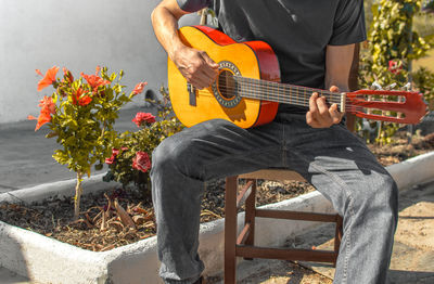 Midsection of man playing guitar in park