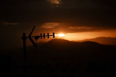 Silhouette telephone pole against sky during sunset