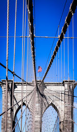 Low angle view of suspension bridge against clear blue sky