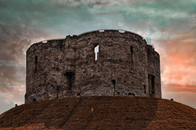 Low angle view of fort against cloudy sky