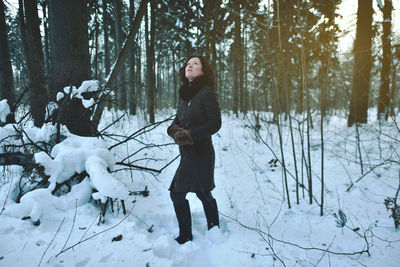 Full length of young woman standing in forest during winter