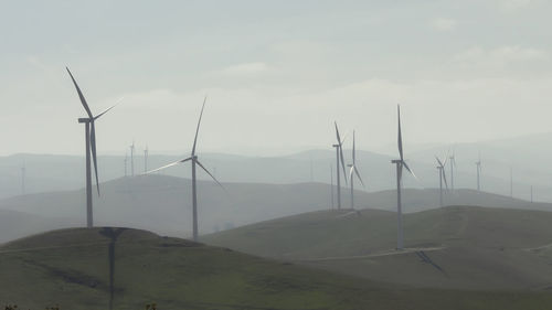 Wind turbines on land against sky