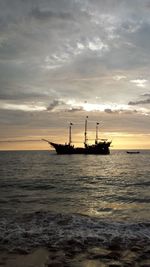 Silhouette ship in sea against sunset sky