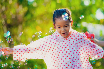 Girl wearing raincoat standing in park during rainy season