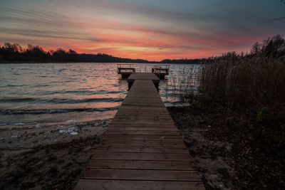 Pier over lake against sky during sunset