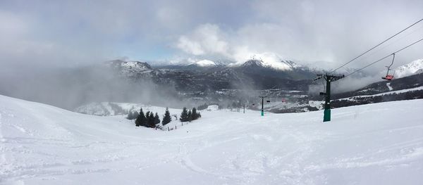 Ski lift over snow covered mountains against sky