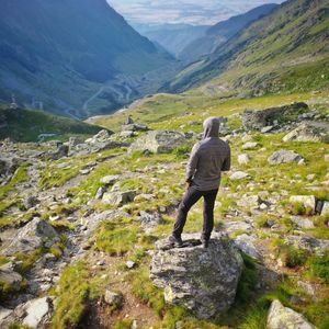 Rear view of man standing on rock against valley