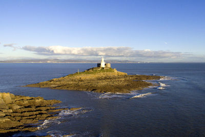 Lighthouse amidst sea and buildings against sky