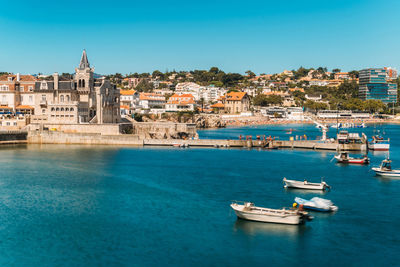 Sailboats in sea against buildings in city