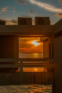 Building by sea against sky during sunset