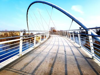 Footbridge over river against sky in city