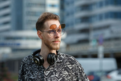 Portrait of a young man in sunglasses and headphones against the background of a modern city