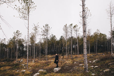 Man standing by trees in forest against clear sky