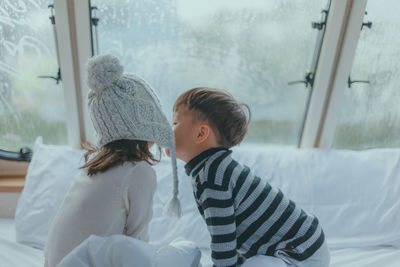 Brother kissing sister on bed at home