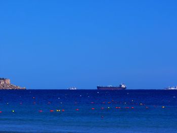 Sailboat on sea against clear blue sky