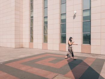 Full length of woman with bicycle against building in city