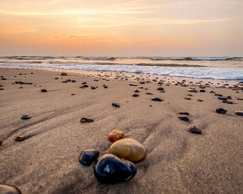 Surface level of pebbles on beach against sky during sunset