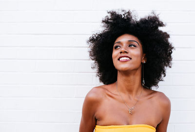 Portrait of smiling woman standing against wall