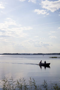 Man sitting in sea against sky