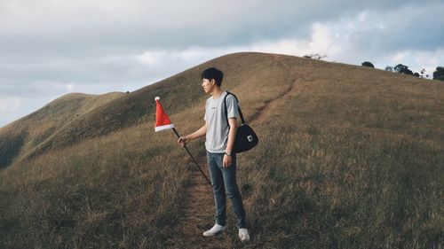 Rear view of girl walking on hill against cloudy sky