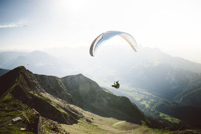 People paragliding against mountain range against sky