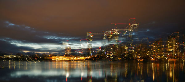 Multiple image of illuminated buildings by sea against sky at night