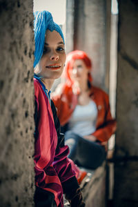 Portrait of young woman standing against wall