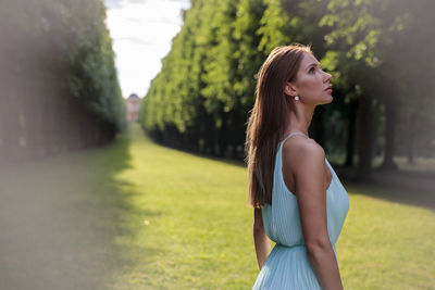 Young woman standing against trees